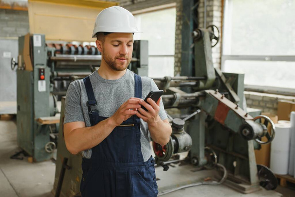 Management team, engineer, or foreman. Standing checking job information about industrial production management within the factory by phone. Teamwork concept. - Zdjęcie, obraz