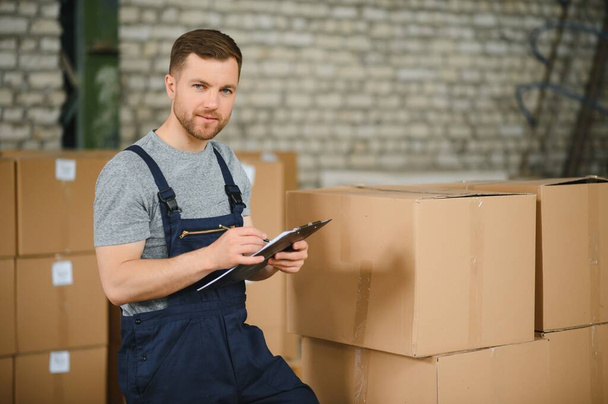 Warehouse worker carrying a carton for delivery to production stock - Foto, Bild