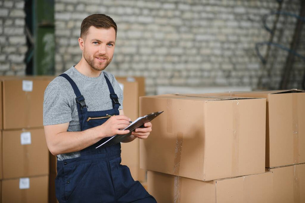 Warehouse worker carrying a carton for delivery to production stock - Photo, Image