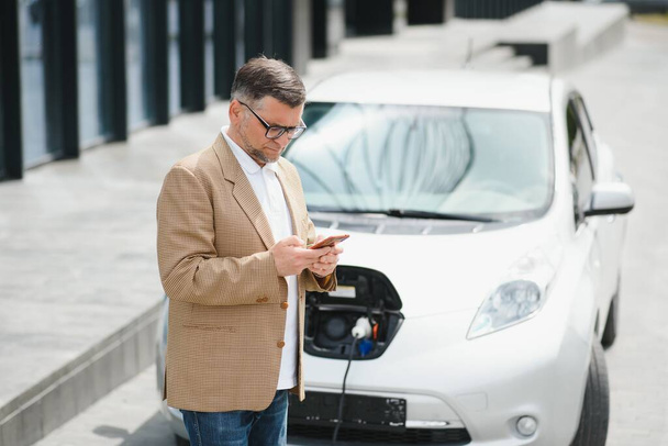 a businessman charges an electric car. - 写真・画像