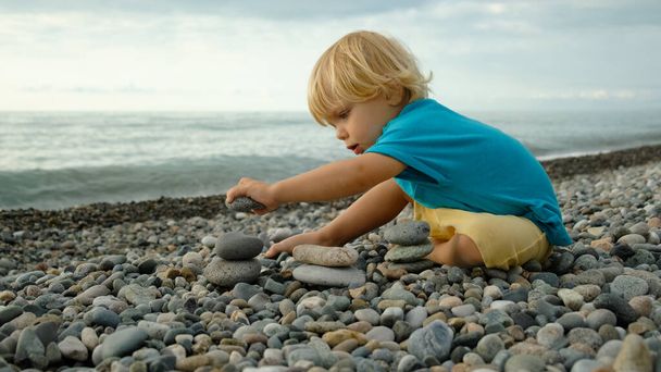 Lapsi leikkii kivillä rannalla. Laadukas 4k kuvamateriaalia - Valokuva, kuva
