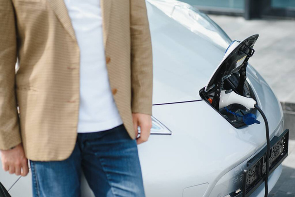 Man charges an electric car at the charging station. - 写真・画像