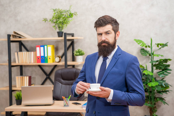 confident bearded businessman drinking coffee in the office with copy space, coffee break. - Fotó, kép