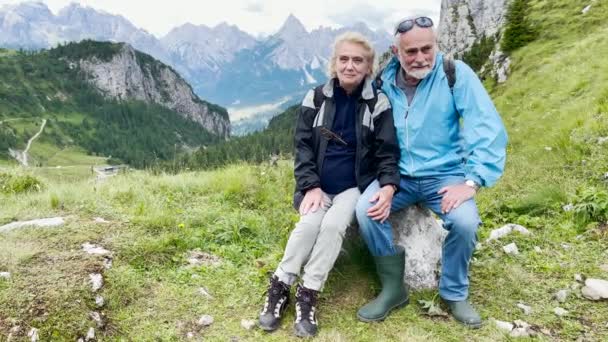 Пожилая пара отдыхает во время горной экскурсии в Альпах, летний сезон. - Кадры, видео