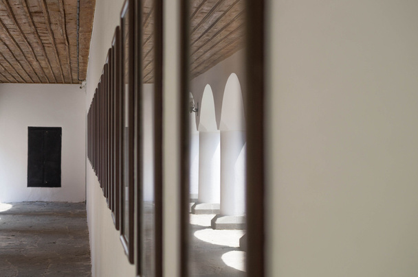 Tiro artístico de um antigo corredor onde as colunas são refletidas pelo vidro de uma imagem
 - Foto, Imagem