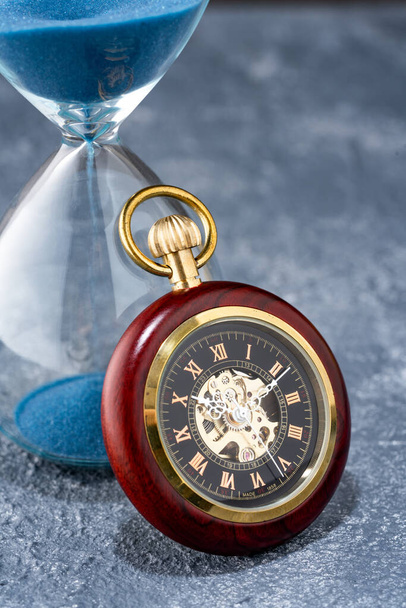 Reloj de bolsillo y reloj de arena en la mesa - Foto, Imagen