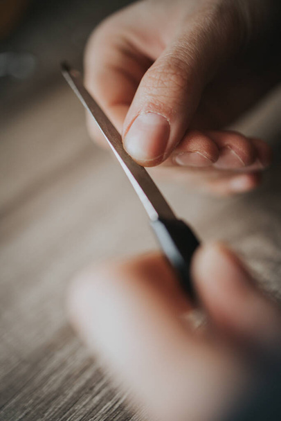 A closeup shot of a woman's hand as she fixes her nails with a nail file - Photo, Image