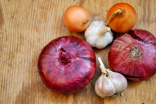 Cebollas rojas y bulbo con ajo orgánico entero en mesa de madera
 - Foto, imagen