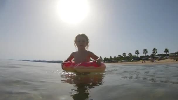 Malá dívka plovoucí a plavající s nafukovacím kroužkem v moři - Záběry, video