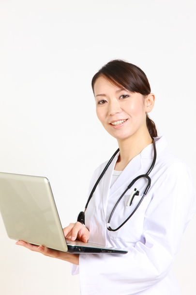 Young Japanese female doctor with laptop computer smiles - Foto, immagini