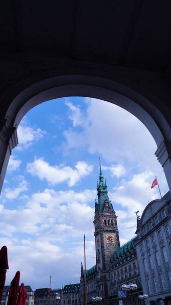 A vertical shot of Hamburg City Hall and the surrounding buildings seen from an arched entrance - Photo, image