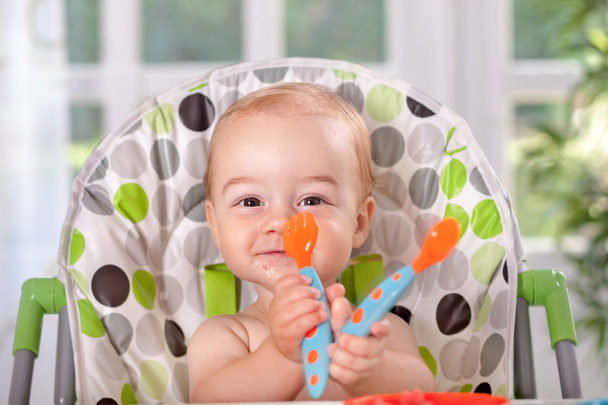 Smiling beautiful baby eating with spoon and fork - Фото, зображення