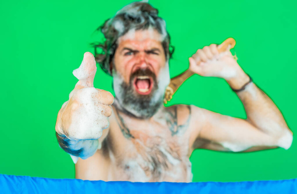 Бородатый мужчина, намыленный пеной в душе, показывает большой палец вверх. Мытье тел. Уход за волосами. СПА - Фото, изображение
