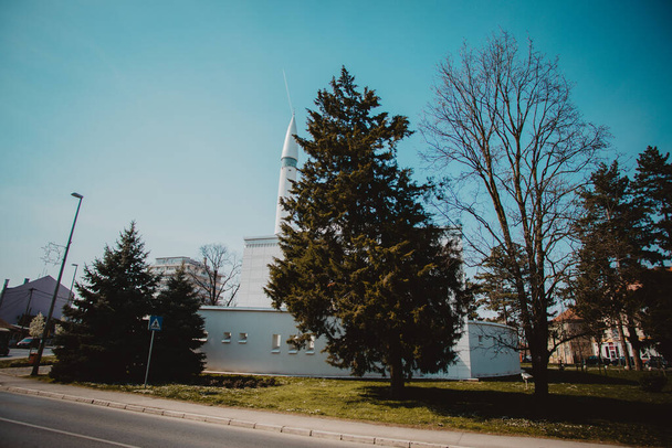 A White mosque in behind the trees under blue sky in Brcko, Bosnia and Herzegovina - Foto, immagini