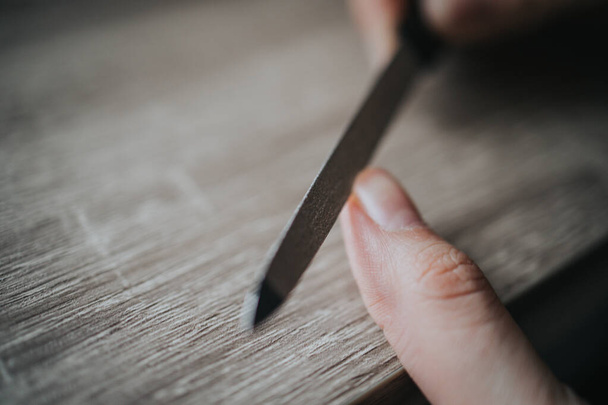 A closeup shot of a woman's hand as she fixes her nails with a nail file - Photo, image