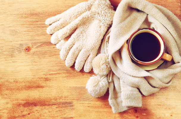 Cup of black coffee with  a warm scarf  on wooden background. filreted image - Foto, Bild