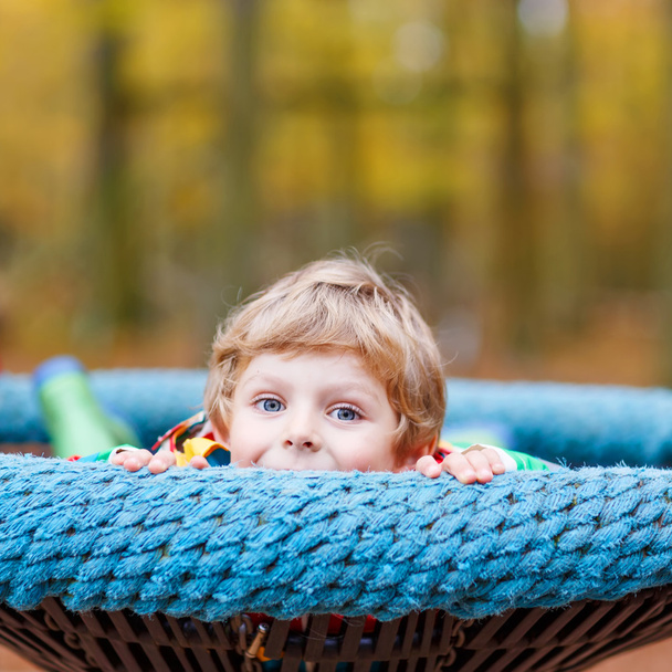 Малыш веселится на осенней детской площадке.
 - Фото, изображение