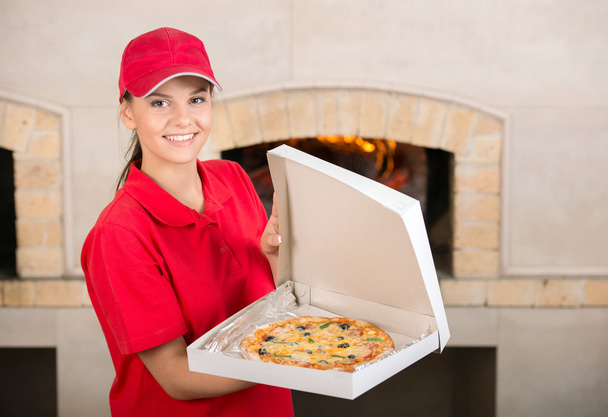 It is tasty. Delivery woman is showing the pizza. - Foto, afbeelding