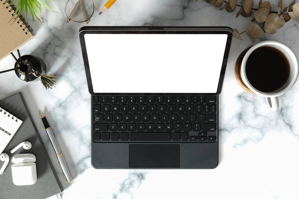 Tableta digital de vista superior con teclado inalámbrico, taza de café y suministros en mesa de mármol. Vista superior, espacio de trabajo femenino. - Foto, imagen