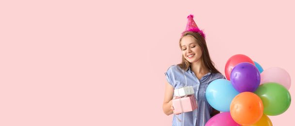 Happy woman with birthday gifts and balloons on pink background with space for text - Photo, Image
