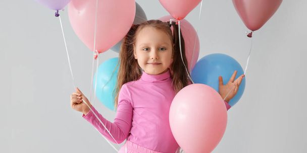 Petite fille mignonne avec des ballons sur fond clair - Photo, image