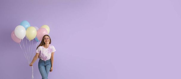 Happy young woman with balloons on lilac background with space for text - Foto, Imagem