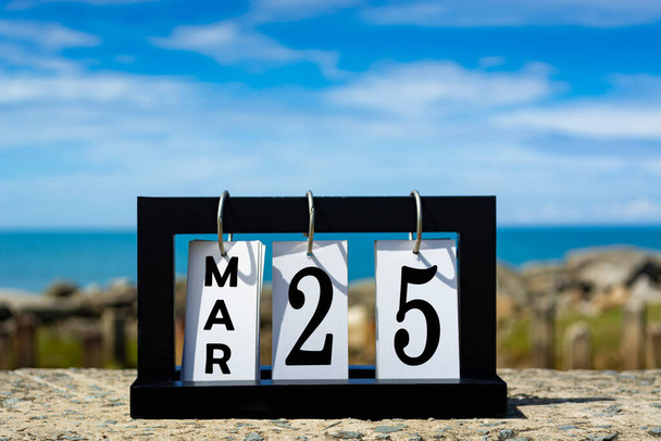 25 марта текст календарной даты на деревянной рамке с размытым фоном океана. Концепция календаря. - Фото, изображение