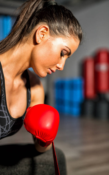 Λάκτισμα θηλυκό μπόξερ κατάρτισης στο γυμναστήριο με τα κόκκινα γάντια. - Φωτογραφία, εικόνα