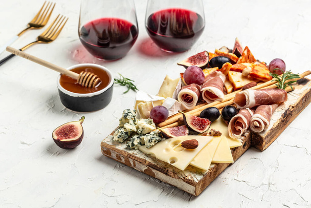 Appetizers table with italian antipasti snacks and wine in glasses. cheese, ham, nuts, fruit, bread sticks. Delicious balanced food concept. - Zdjęcie, obraz