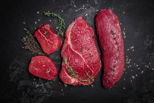 Beef tenderloin fillet with rosemary and spices on a dark background. Preparing fresh beef steak ready to cook, Long banner format. top view. - 写真・画像