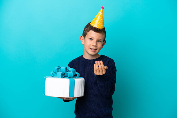 青い背景に孤立した誕生日ケーキを持っている小さな男の子が手を携えて来るように誘います。来てくれて嬉しい - 写真・画像