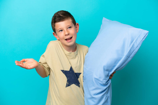Malý chlapec v pyžamu izolované na modrém pozadí s šokovaným výrazem obličeje - Fotografie, Obrázek