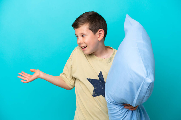 Little boy in pajamas isolated on blue background with surprise expression while looking side - Foto, Imagem