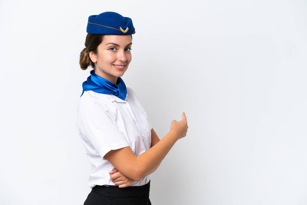 Vliegtuig stewardess Kaukasische vrouw geïsoleerd op witte achtergrond wijzend terug - Foto, afbeelding