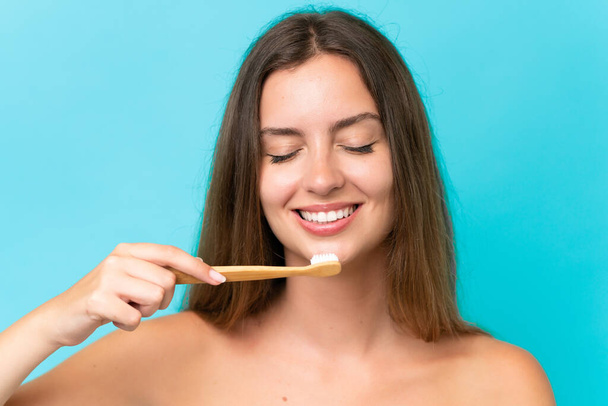 Young caucasian woman isolated on blue background with a toothbrush and happy expression - Φωτογραφία, εικόνα