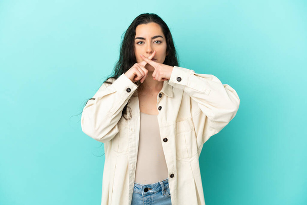 Young caucasian woman isolated on blue background showing a sign of silence gesture - Photo, Image