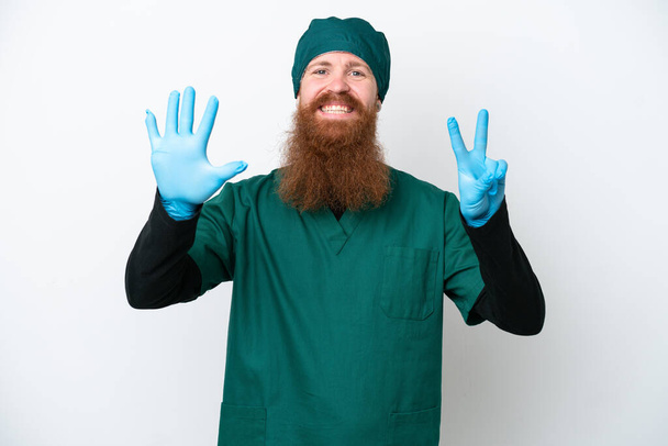 Surgeon redhead man in green uniform isolated on white background counting seven with fingers - Foto, afbeelding
