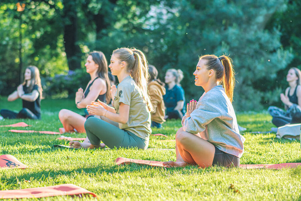 Vilnius, Litauen - 22. Juni 2022: Schöne Mädchen machen Outdoor-Aktivitäten oder Outdoor-Aktivitäten, Yoga oder Fitness auf dem Rasen in einem öffentlichen Park im Sommer - Foto, Bild