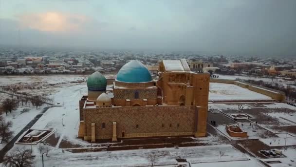 Mauzoleum Khoja Ahmed Yasawi v Turkestánu. Pohled shora z dronu. Zimní večer zapadá slunce pod obzor. Šedé mraky na obloze. Mauzoleum v bílém sněhu. Kazachstán. Svaté místo. - Záběry, video