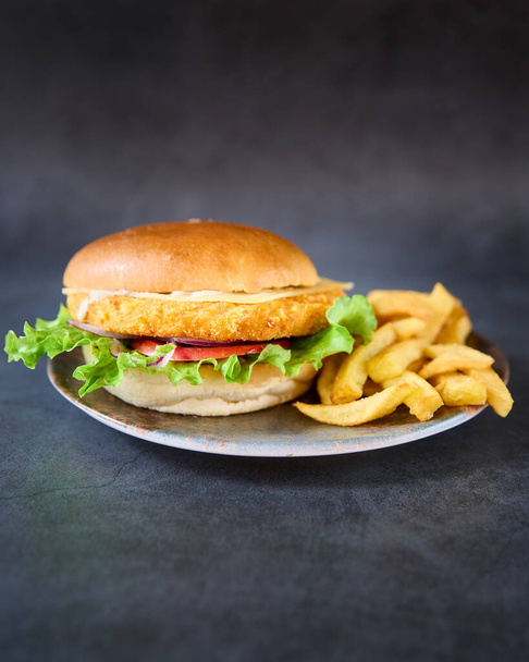 a vertical shot of a Chicken  burger with french fries on a plate. - Foto, Bild
