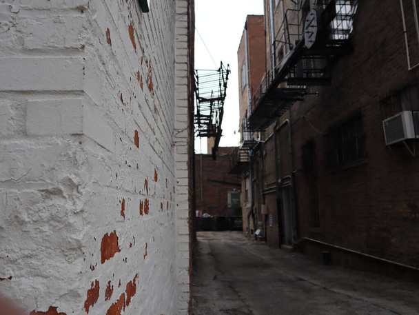 A closeup shot of a white brick wall of a building in a narrow street - Fotó, kép
