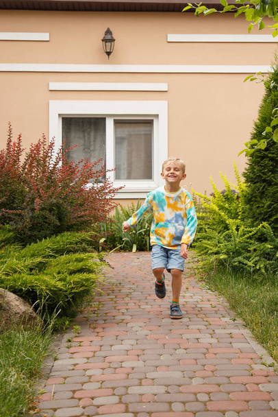 A boy of European appearance walks merrily.A five-year-old boy is walking along the path - Fotoğraf, Görsel