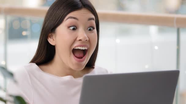 Zamknij się szczęśliwy podekscytowany azjatycki dziewczyna zwycięzca z laptopem świętować triumf dobre wiadomości zakłady z aplikacji online. Udane szczęście kobieta patrząc ekran wygrywa ma nową ofertę pracy krzyki sprawia, że tak gest - Materiał filmowy, wideo