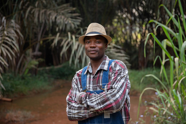 Portret rolnika pozującego na świeżym powietrzu ze złożonymi ramionami, uśmiechnięty, odnoszący sukcesy afrykański biznesmen. - Zdjęcie, obraz