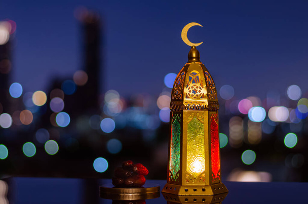 ラマダーンの聖月のイスラム教徒の饗宴のための日付の果物の上と小皿の上に月のシンボルを持っているランタンとイスラムの新年の概念. - 写真・画像