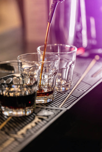 Barman pouring fresh alcoholic drink into the glasses on the bar counter - Valokuva, kuva