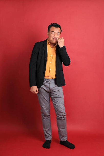 The Asian middle aged man standing on the red background. - Fotó, kép