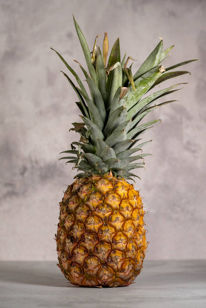 A vertical shot of a ripe pineapple isolated on a gray background - Foto, afbeelding