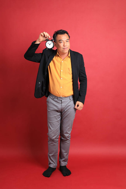 L'uomo asiatico di mezza età in piedi sullo sfondo rosso. - Foto, immagini