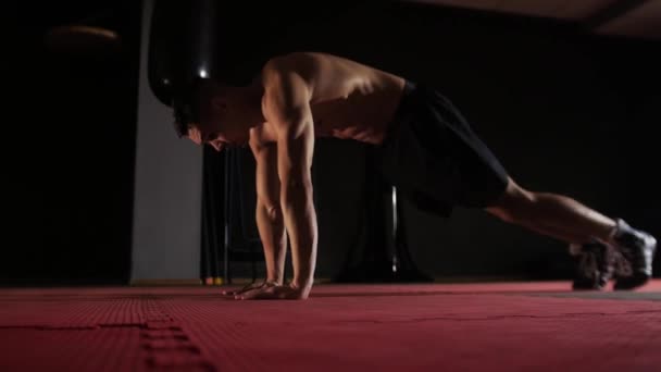 Fitness tréning - fitt félmeztelen férfi dolgozik a padlón. Középső felvétel - Felvétel, videó
